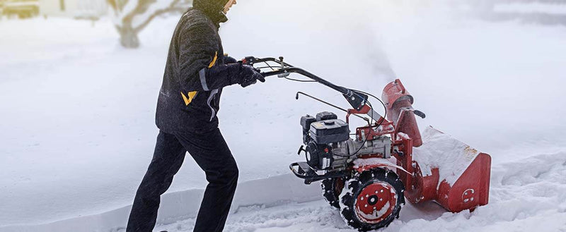 Osoba odśnieża odśnieżarką drogę.